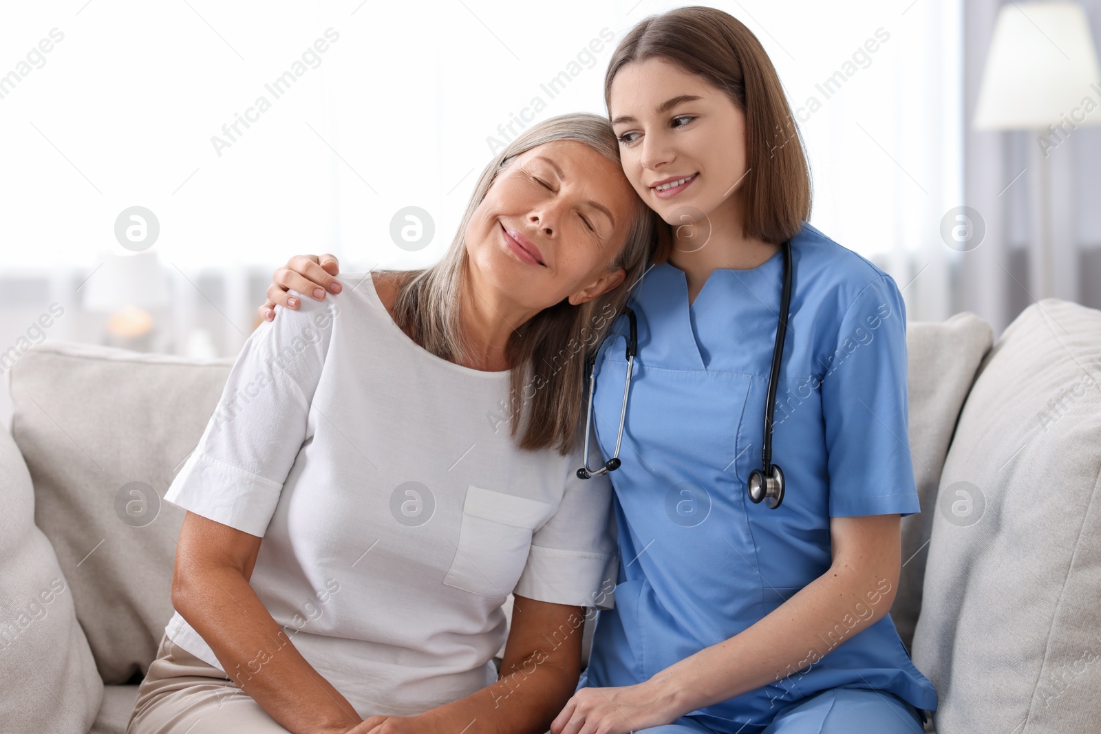 Photo of Smiling healthcare worker supporting senior patient indoors