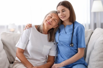 Smiling healthcare worker supporting senior patient indoors