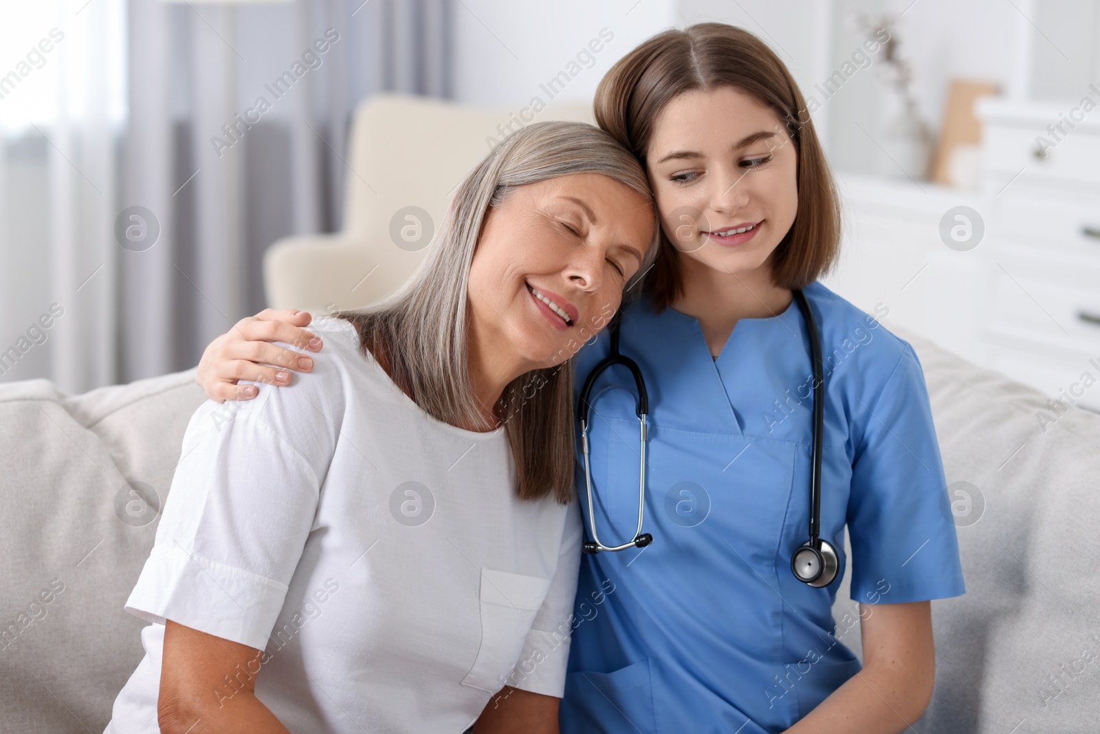 Photo of Smiling healthcare worker supporting senior patient indoors