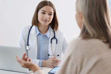 Photo of Smiling healthcare worker consulting senior patient in hospital