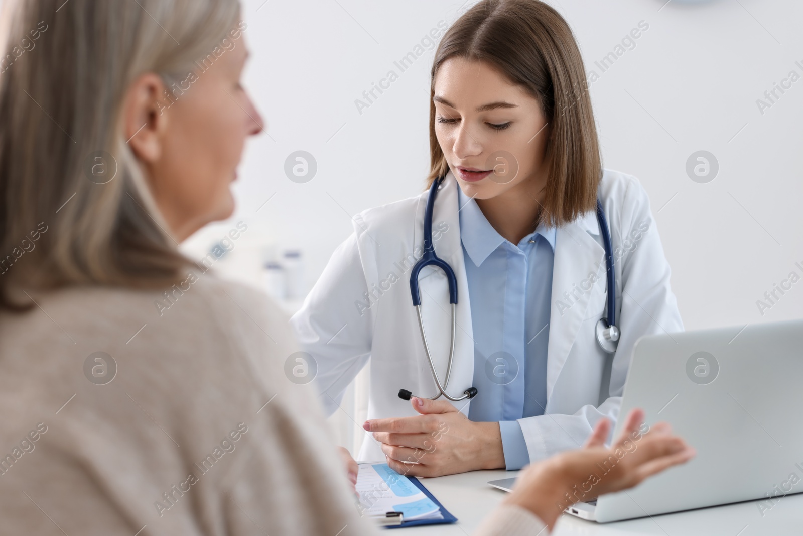 Photo of Young healthcare worker consulting senior patient in hospital