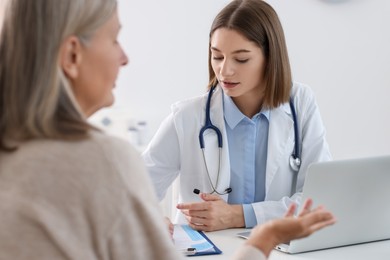 Photo of Young healthcare worker consulting senior patient in hospital