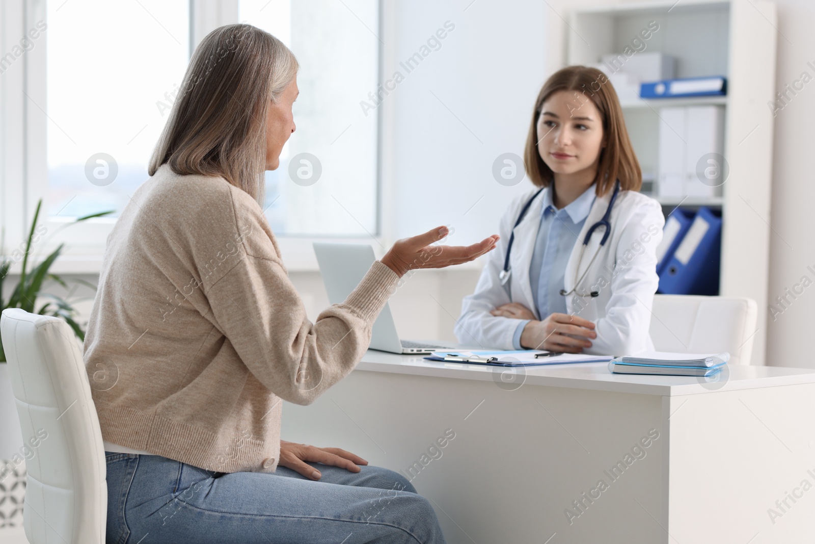 Photo of Young healthcare worker consulting senior patient in hospital