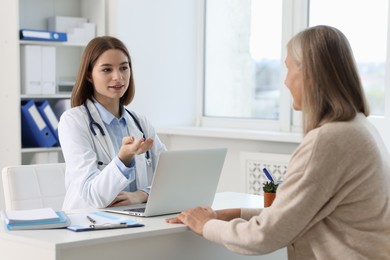 Photo of Young healthcare worker consulting senior patient in hospital