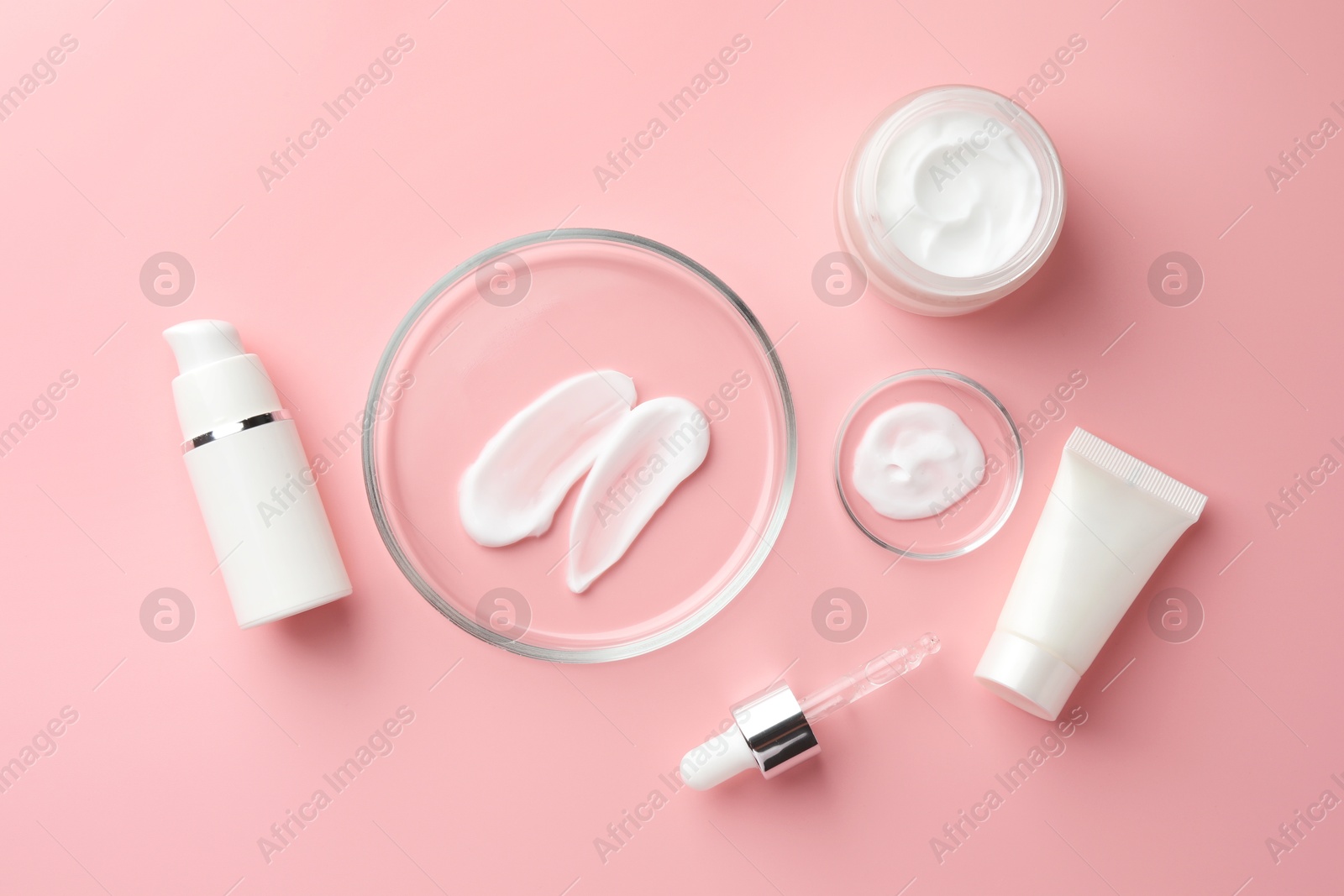 Photo of Petri dishes with cosmetic products and pipette on pink background, flat lay