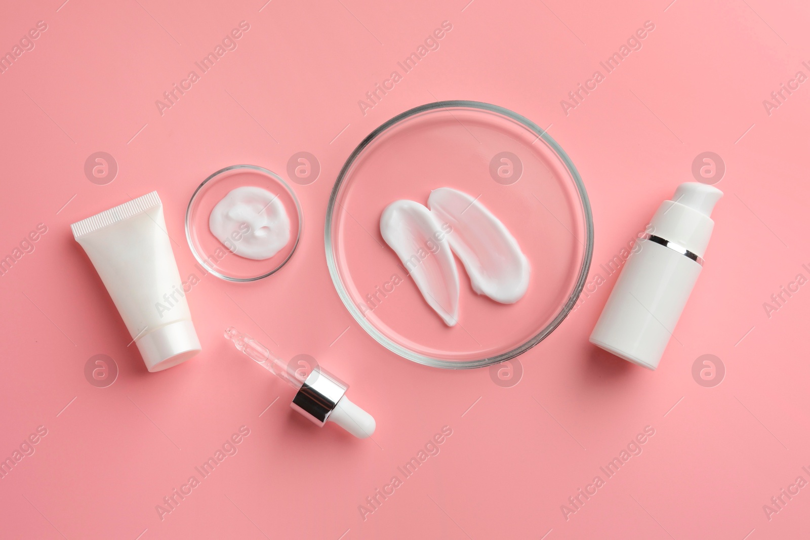 Photo of Petri dishes with cosmetic products and pipette on pink background, flat lay