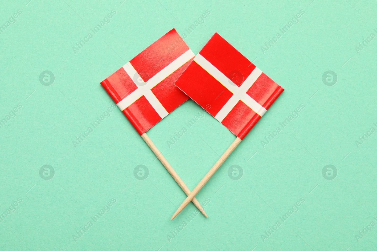 Photo of Small paper flags of Denmark on turquoise background, top view