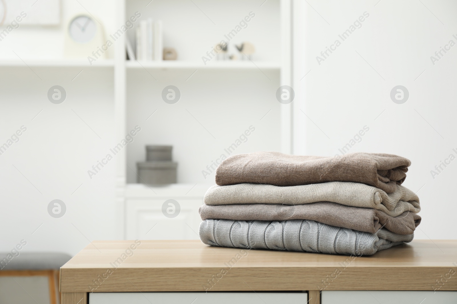 Photo of Stack of clean clothes on wooden dresser indoors