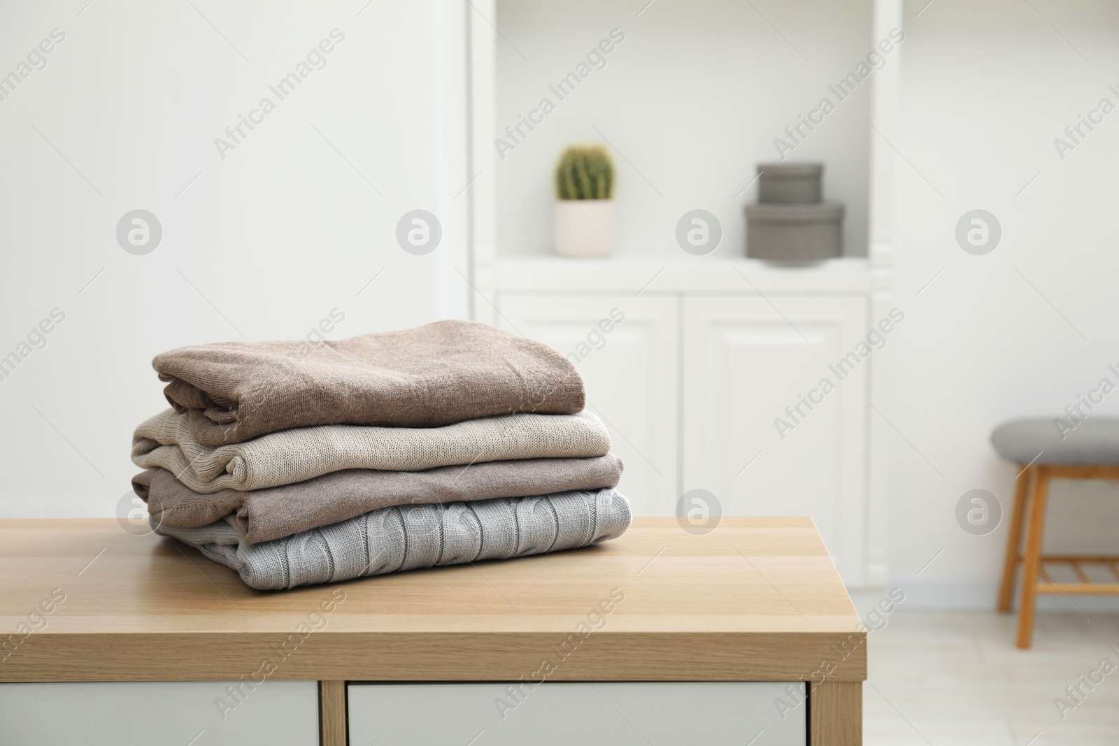 Photo of Stack of clean clothes on wooden dresser indoors