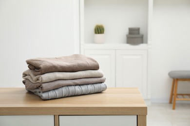 Stack of clean clothes on wooden dresser indoors