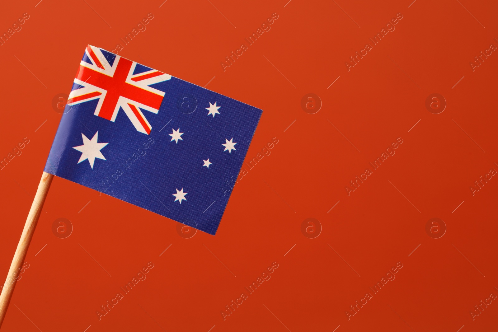 Photo of Small paper flag of Australia on orange background, space for text