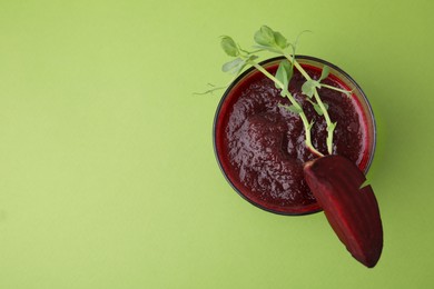 Tasty beetroot smoothie with microgreens in glass on green table, top view and space for text. Vegan drink