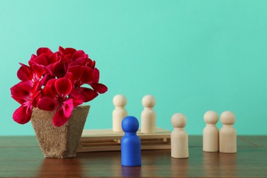 Blue piece near wooden ones and beautiful flower on table against turquoise background