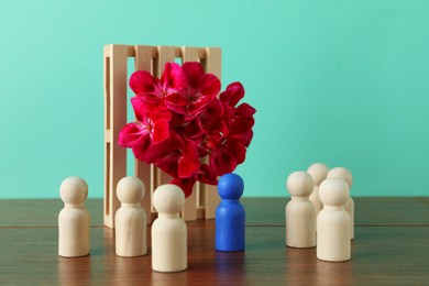 Blue piece among wooden ones and beautiful flower on table against turquoise background