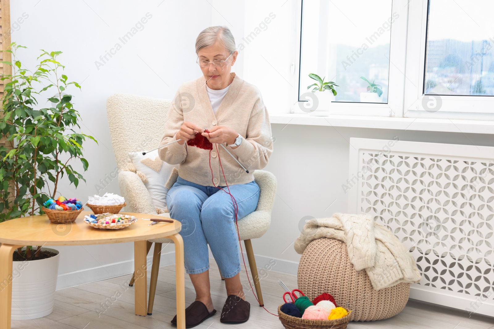 Photo of Beautiful senior woman knitting on armchair at home