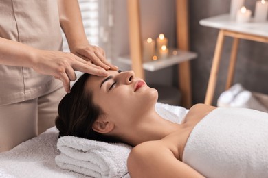 Photo of Attractive woman enjoying face massage in spa salon, closeup