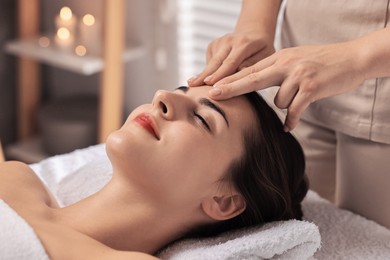 Photo of Attractive woman enjoying face massage in spa salon, closeup