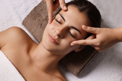 Photo of Attractive woman enjoying face massage, above view. Beauty procedure