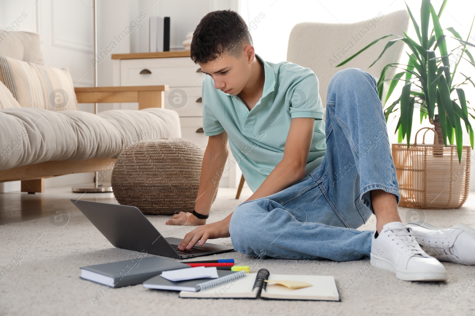 Photo of Portrait of teenage boy with laptop and books at home