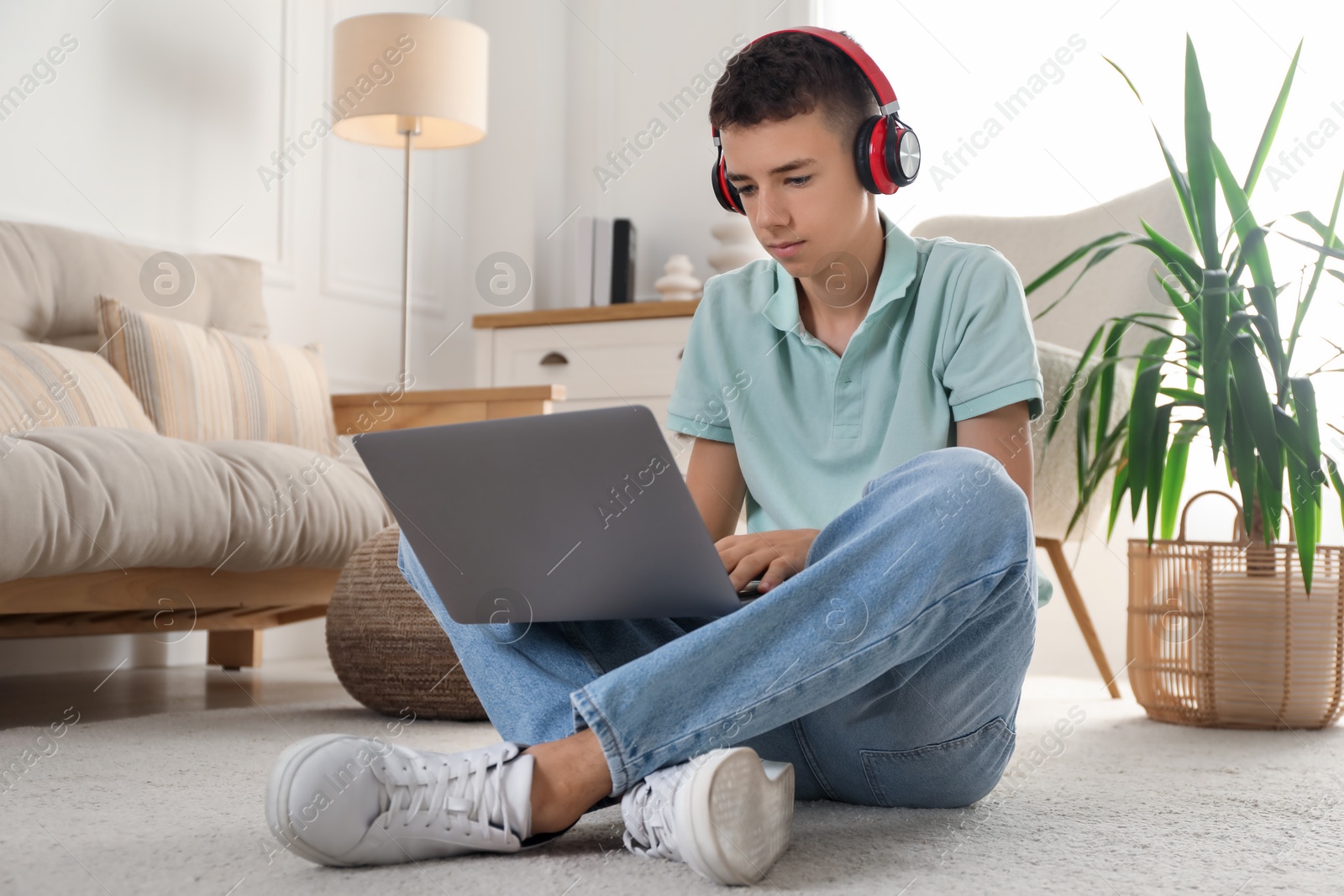 Photo of Portrait of teenage boy with laptop and headphones at home