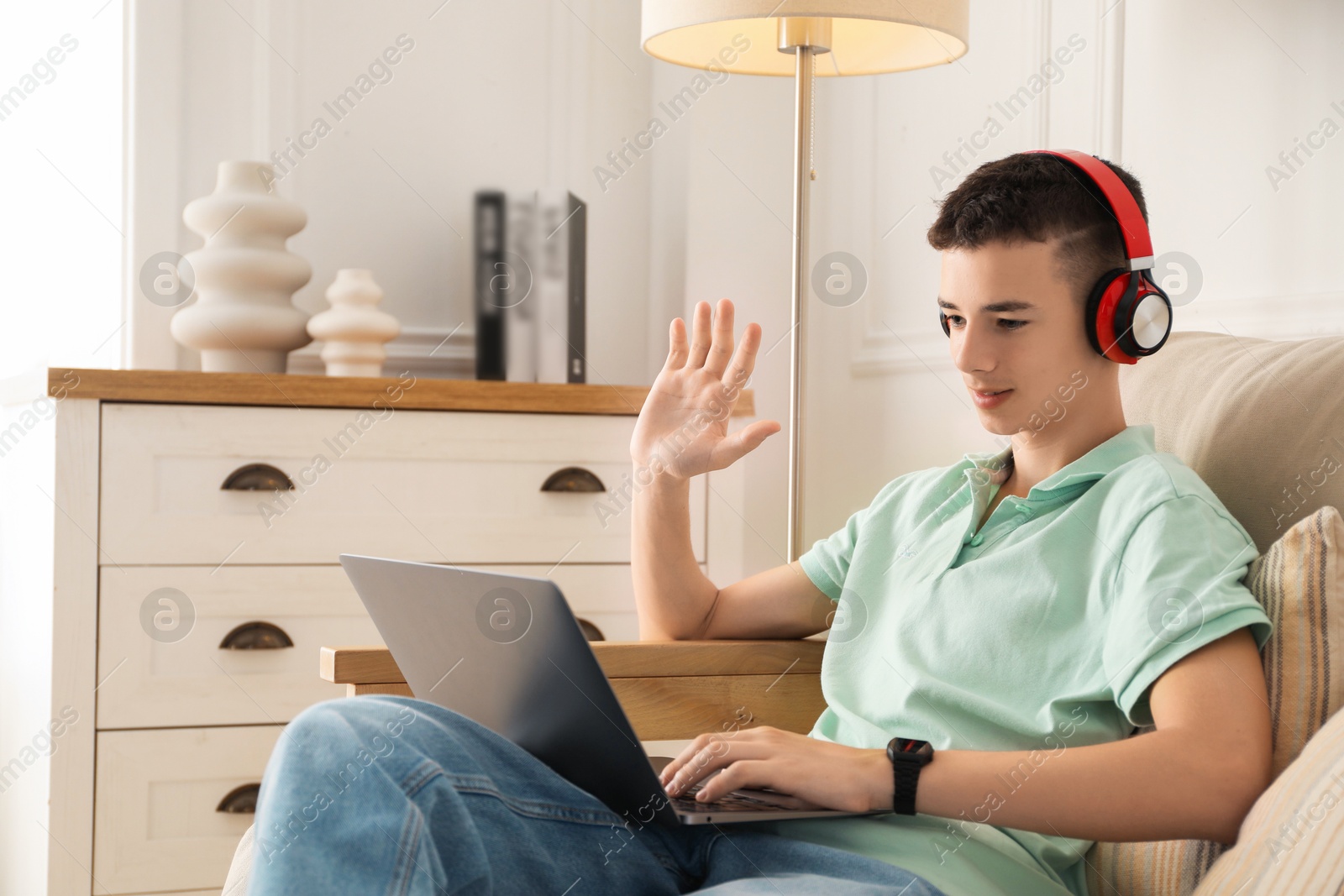 Photo of Portrait of teenage boy with laptop and headphones at home