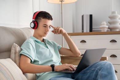 Photo of Portrait of teenage boy with laptop and headphones at home