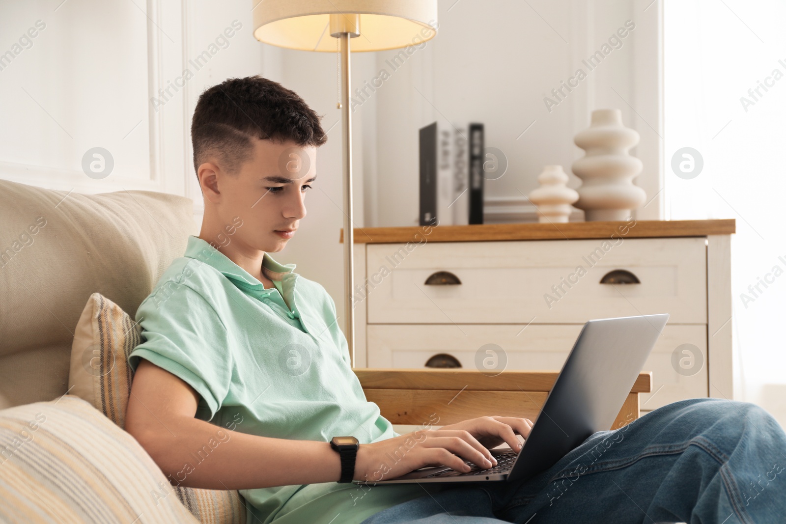 Photo of Portrait of teenage boy with laptop at home