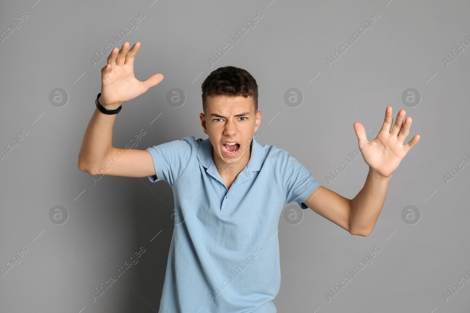 Photo of Portrait of angry teenage boy on grey background