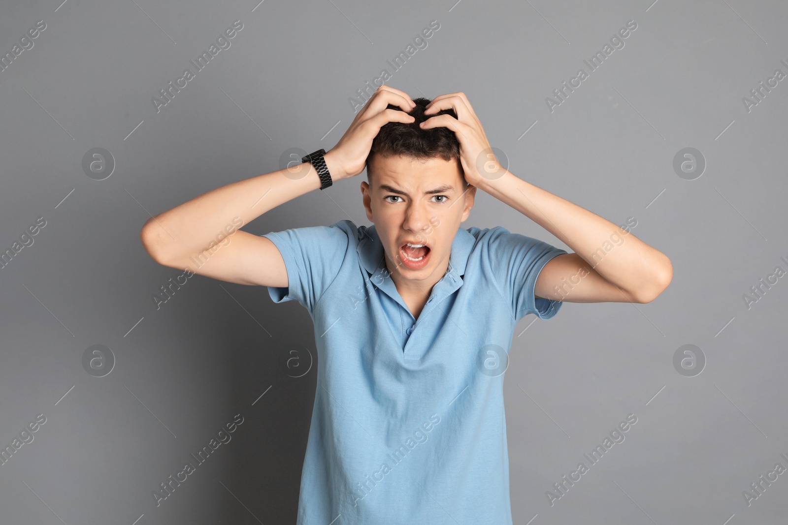 Photo of Portrait of angry teenage boy on grey background