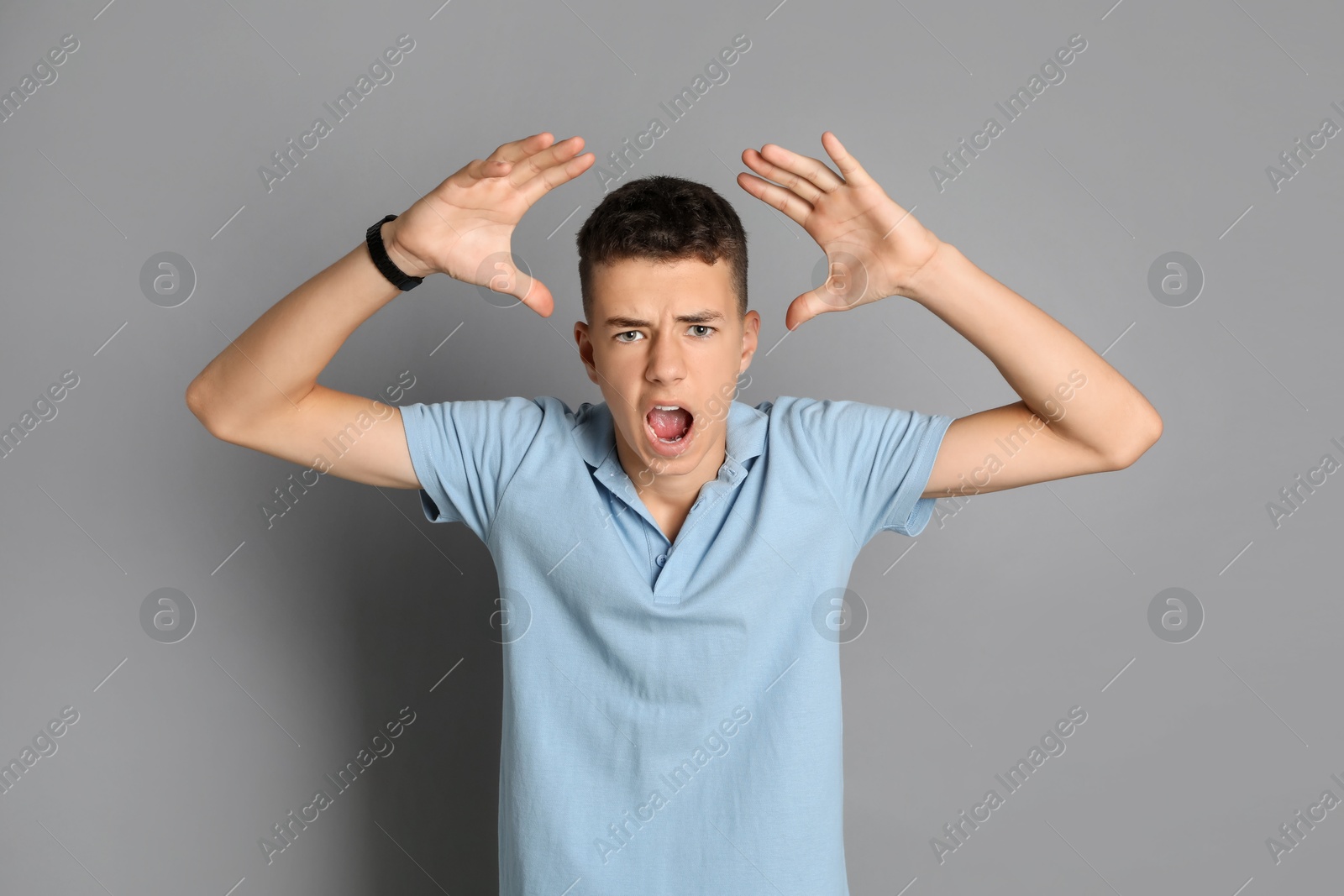 Photo of Portrait of angry teenage boy on grey background