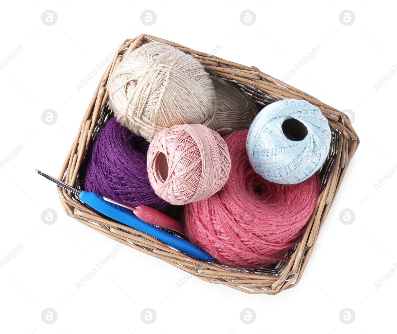 Photo of Many colorful yarns and crochet hooks in wicker basket isolated on white, top view