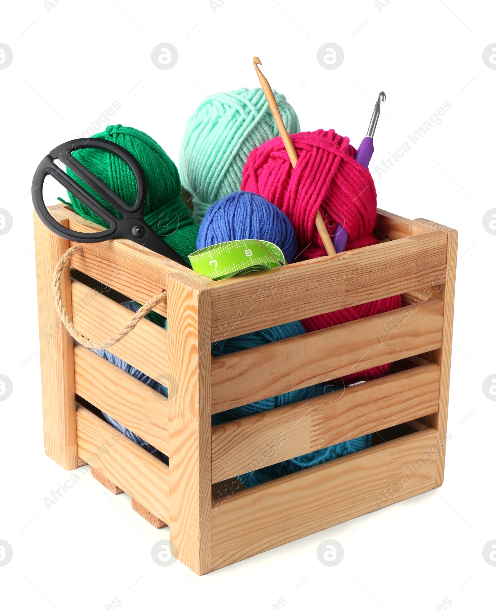 Photo of Colorful yarns and crochet materials in wooden crate isolated on white