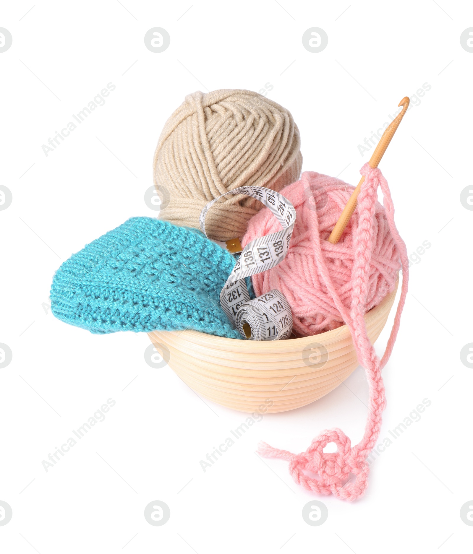 Photo of Colorful yarns, pattern sample, measuring tape and crochet hook in wooden bowl isolated on white