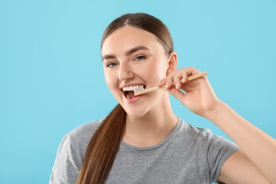 Photo of Beautiful woman brushing her teeth on light blue background