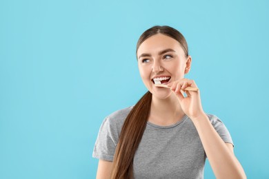 Photo of Beautiful woman brushing her teeth on light blue background, space for text