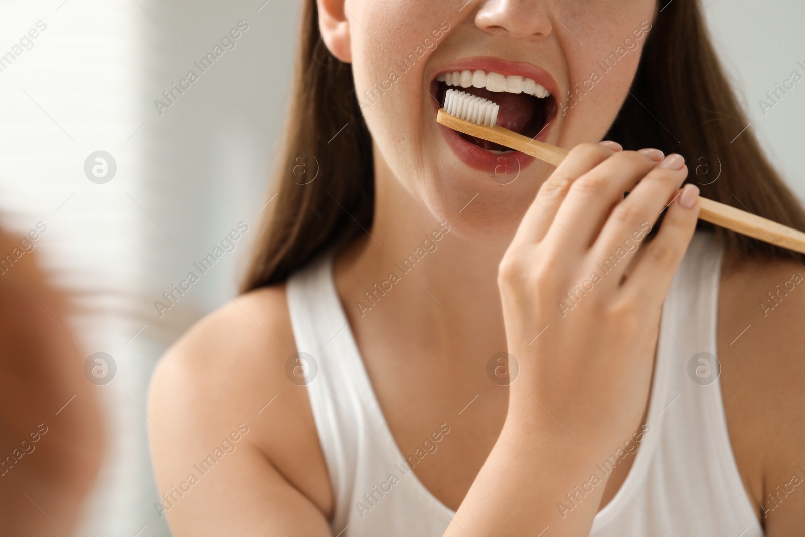 Photo of Woman brushing her teeth in bathroom, closeup