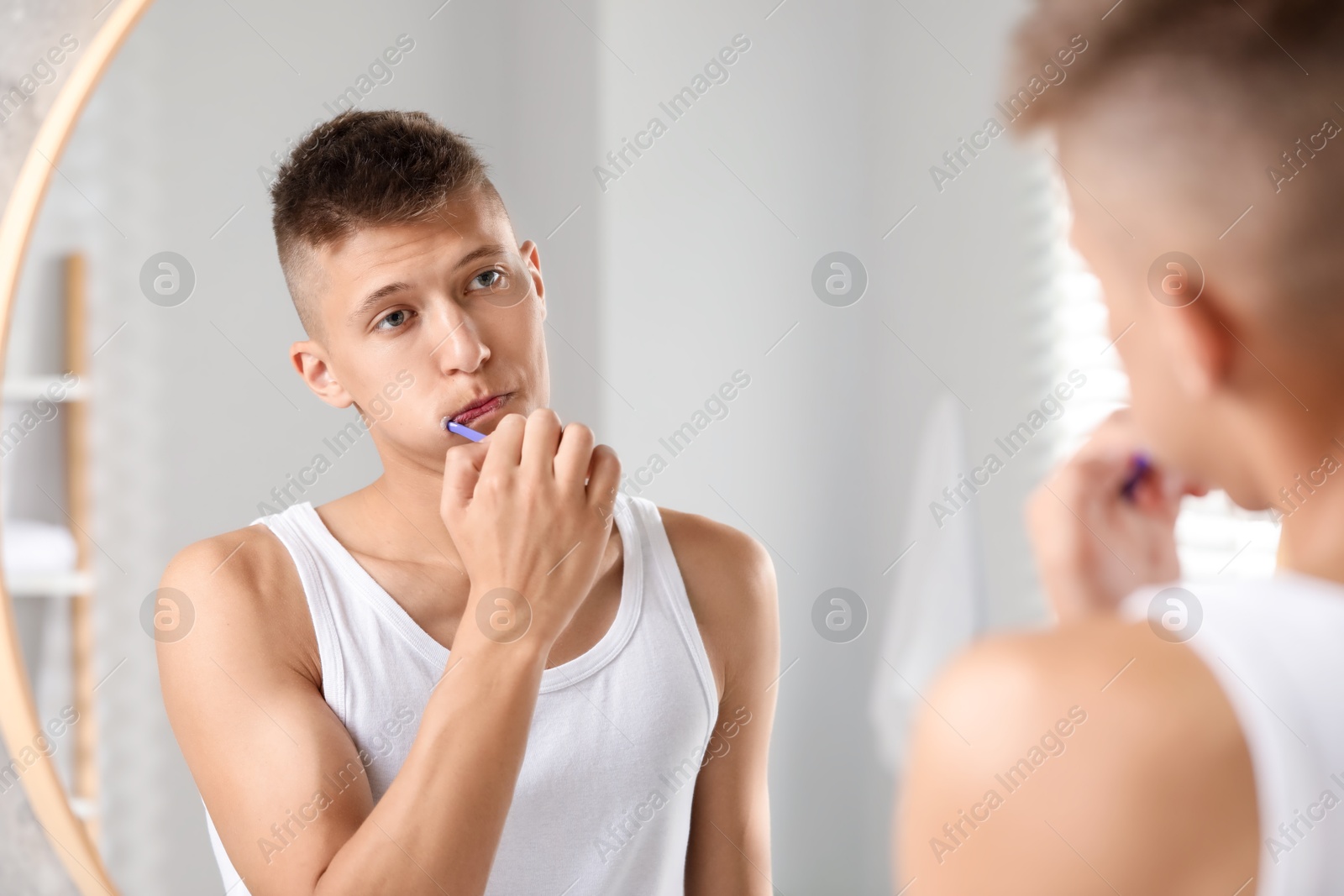 Photo of Young man brushing his teeth in bathroom