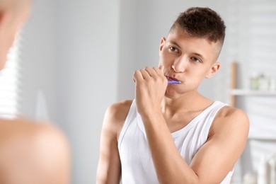 Photo of Young man brushing his teeth in bathroom