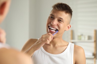 Photo of Young man brushing his teeth in bathroom