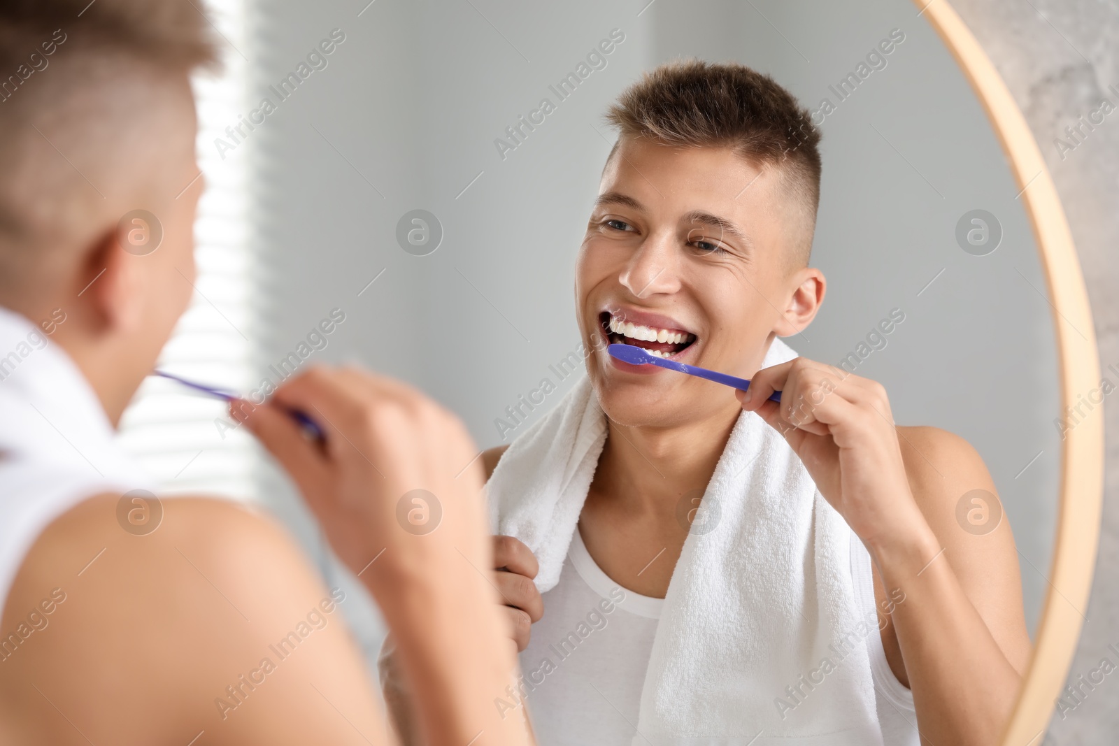 Photo of Young man brushing his teeth in bathroom