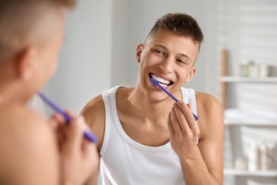 Young man brushing his teeth in bathroom