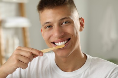 Photo of Young man brushing his teeth in bathroom