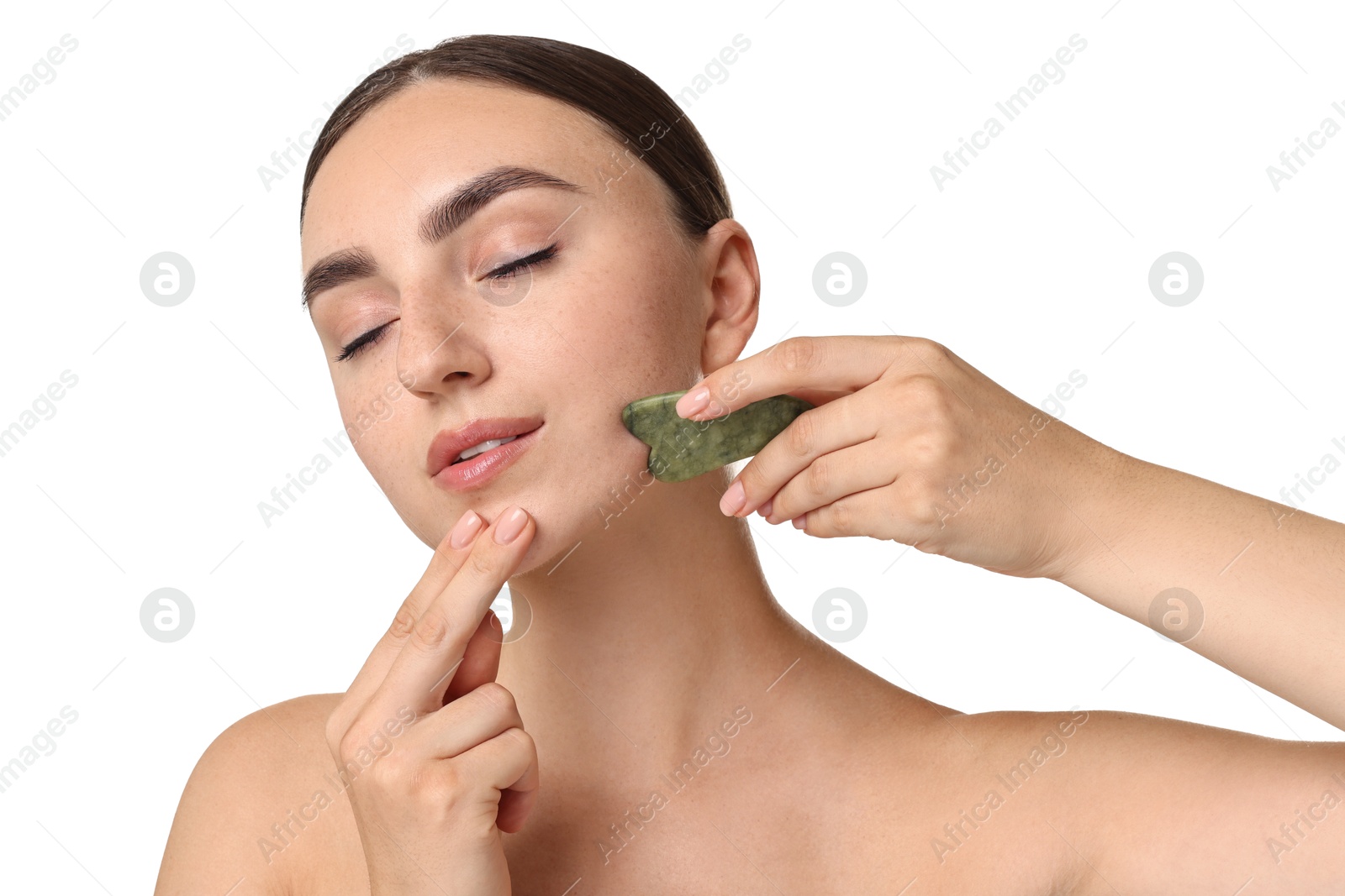 Photo of Beautiful young woman doing facial massage with gua sha tool on white background