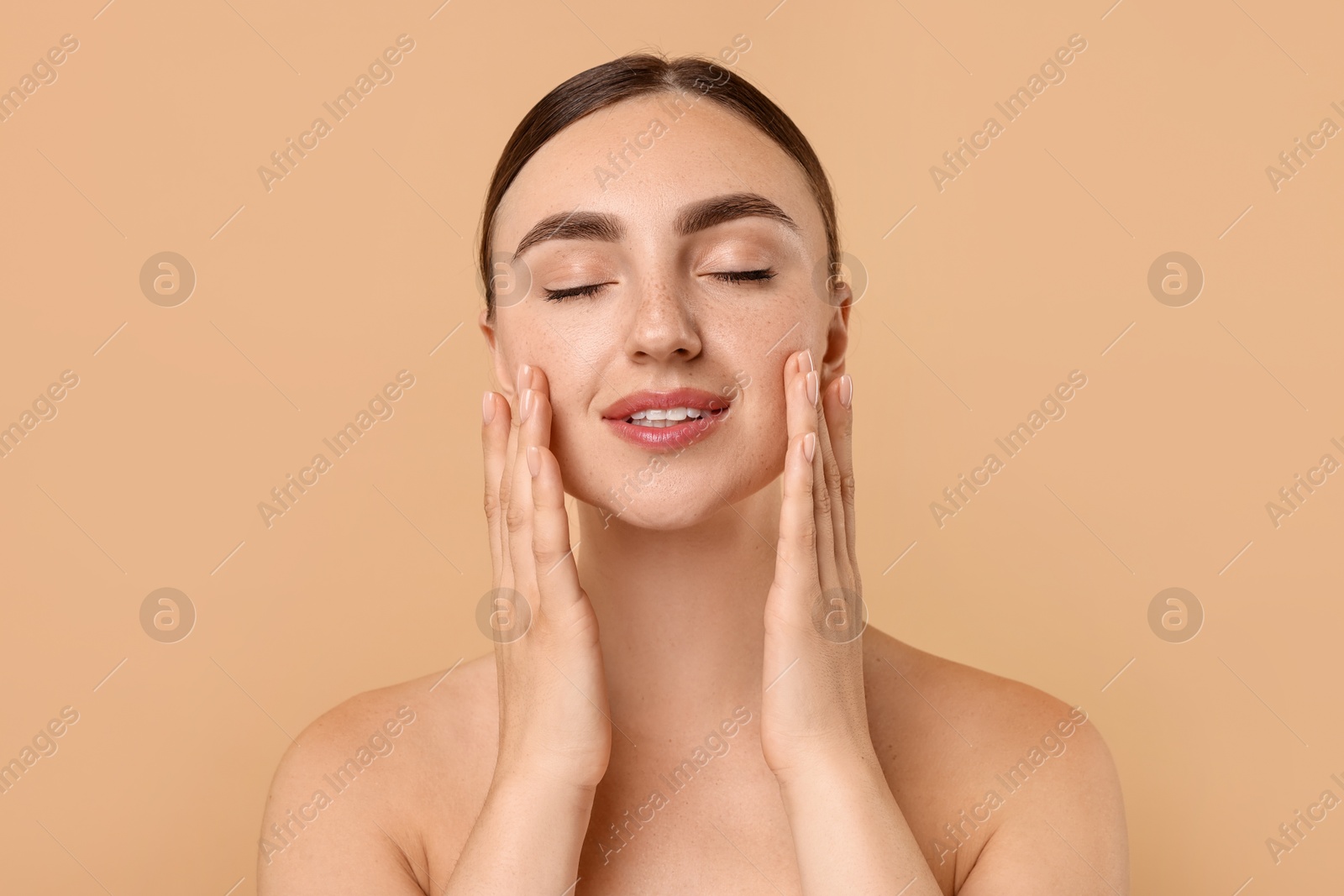 Photo of Beautiful young woman doing facial massage on beige background