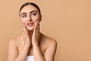 Photo of Face massage. Beautiful young woman with healthy skin on beige background, space for text