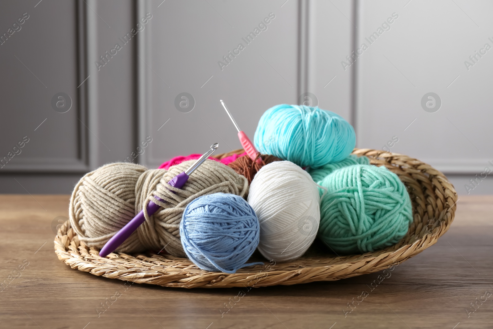 Photo of Different yarns and crochet hooks on wooden table indoors