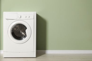 Photo of Washing machine near olive wall, space for text