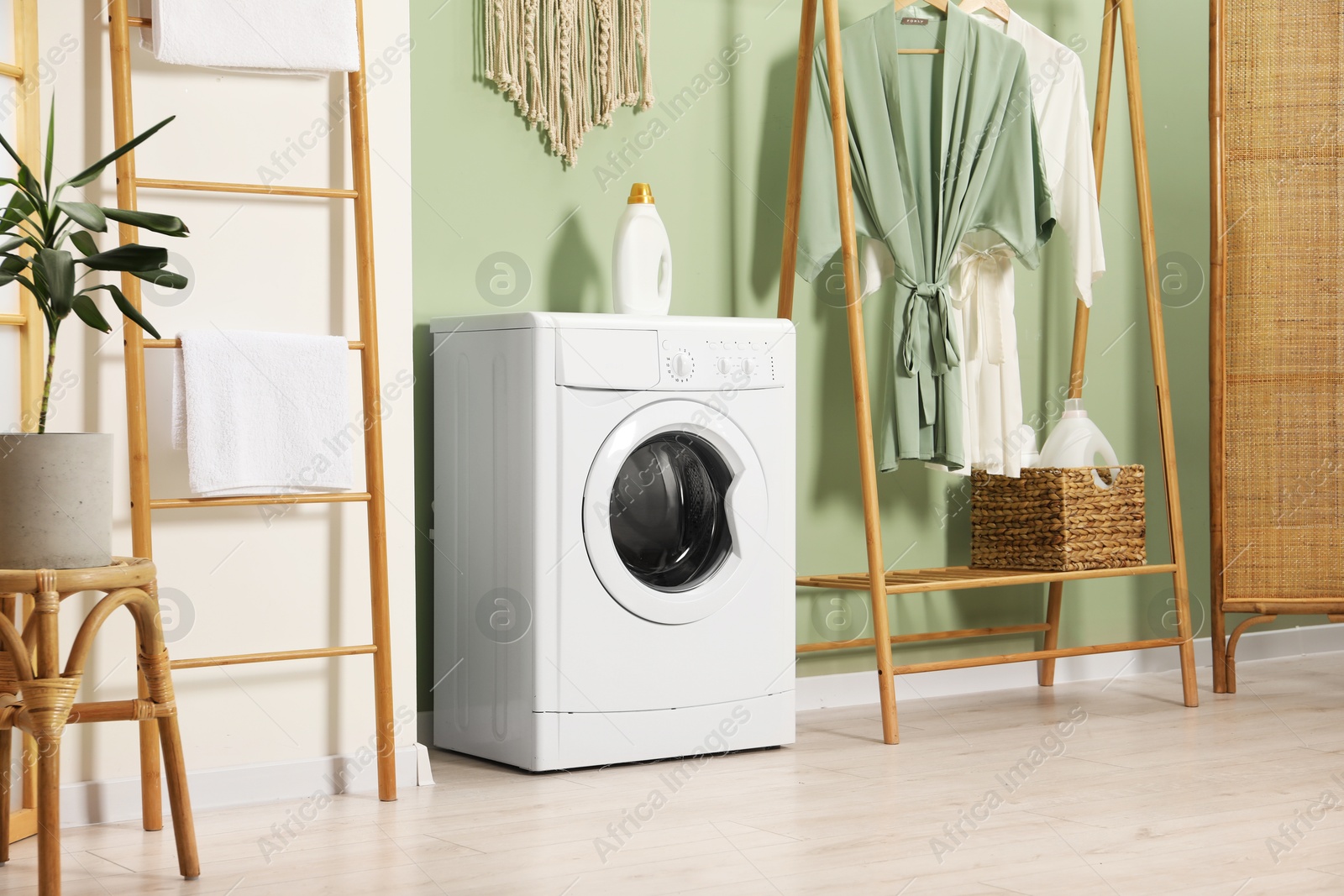 Photo of Washing machine, towels and detergent in laundry room