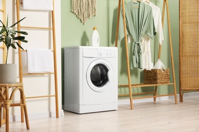 Photo of Washing machine, towels and detergent in laundry room