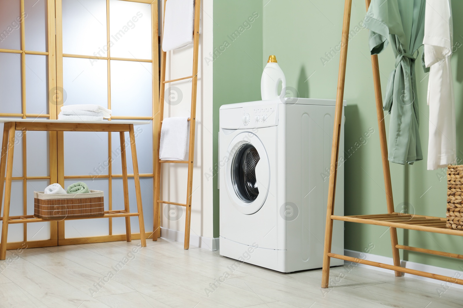 Photo of Washing machine, towels and detergent in laundry room